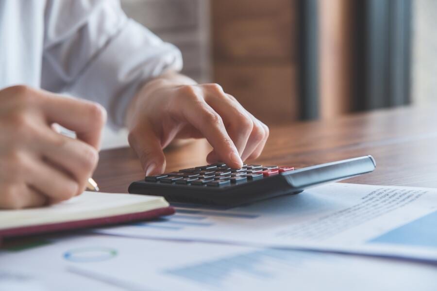 Person using a calculator with financial documents on a desk.