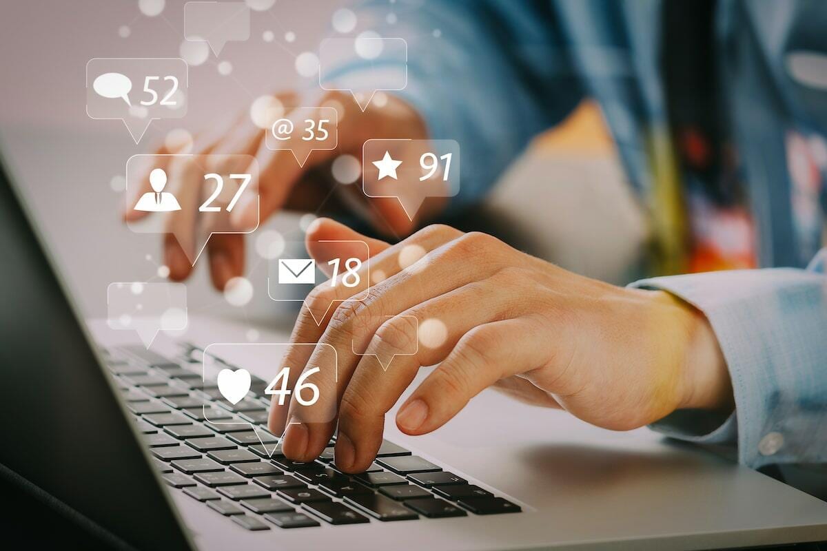 Hands typing on a laptop with social media icons floating above, representing viral marketing engagement.