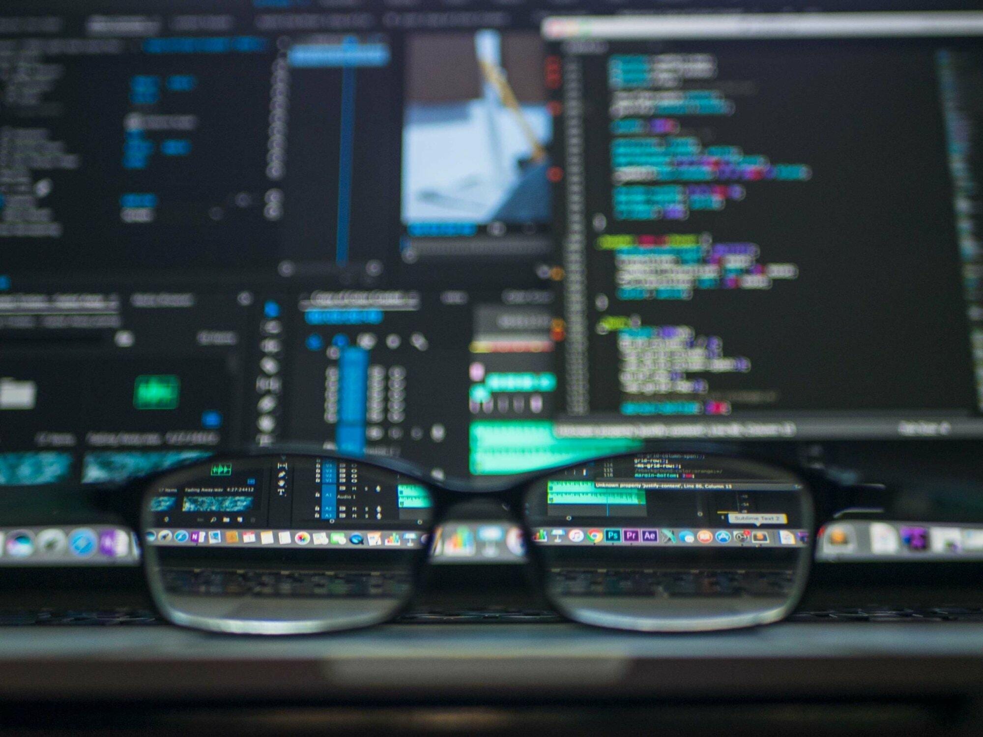 Glasses reflecting computer code on screens, depicting IT services enhancing business growth.