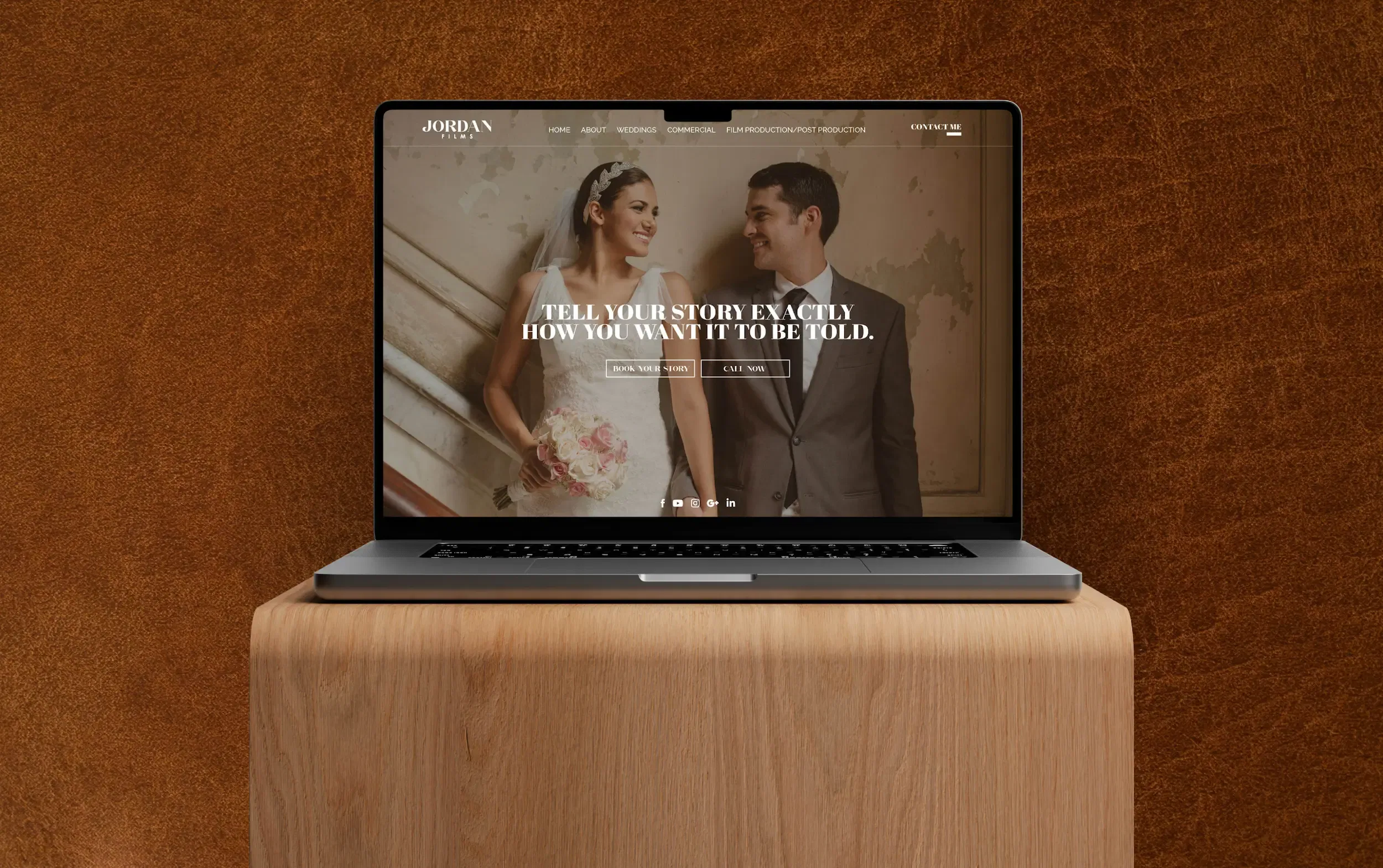 Laptop displaying a wedding website on a wooden stand against a warm brown background.