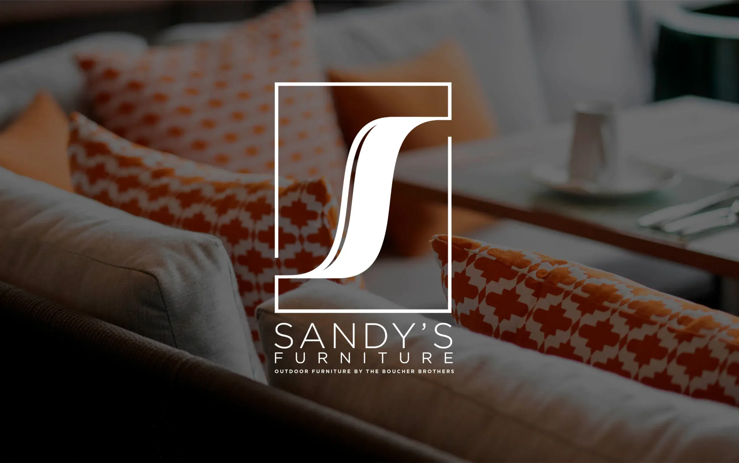 Cozy lounge area with plush sofas and vibrant orange patterned pillows from Sandy's Furniture.