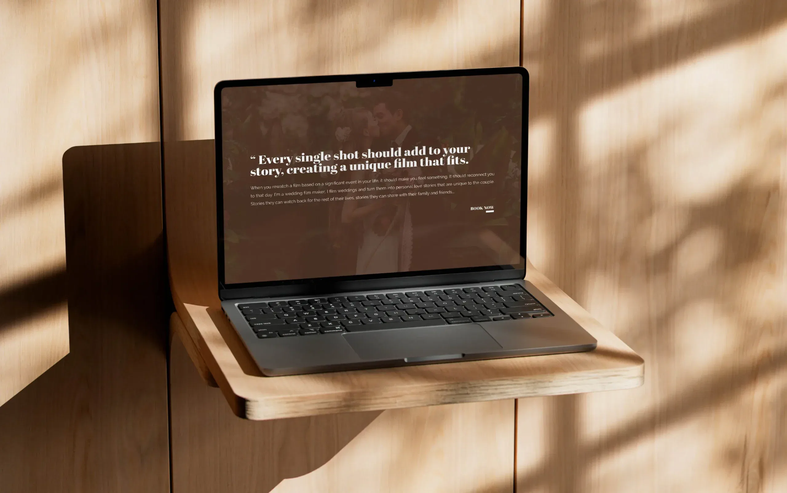 Laptop on a wooden shelf displaying a motivational quote on a sunlit background.