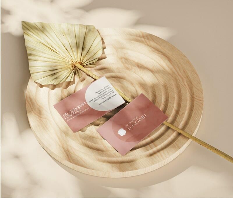 Natural dried leaf on textured wooden plate with elegant business cards in a soft light.