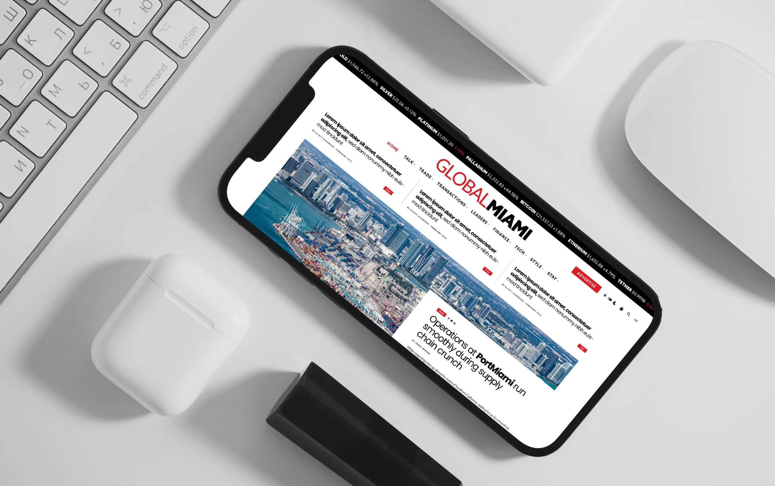 Smartphone displaying a website on a desk alongside a keyboard and earphones.