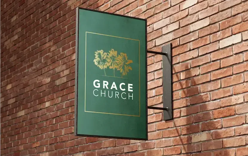 A green signage with gold tree emblem for Grace Church mounted on a brick wall.