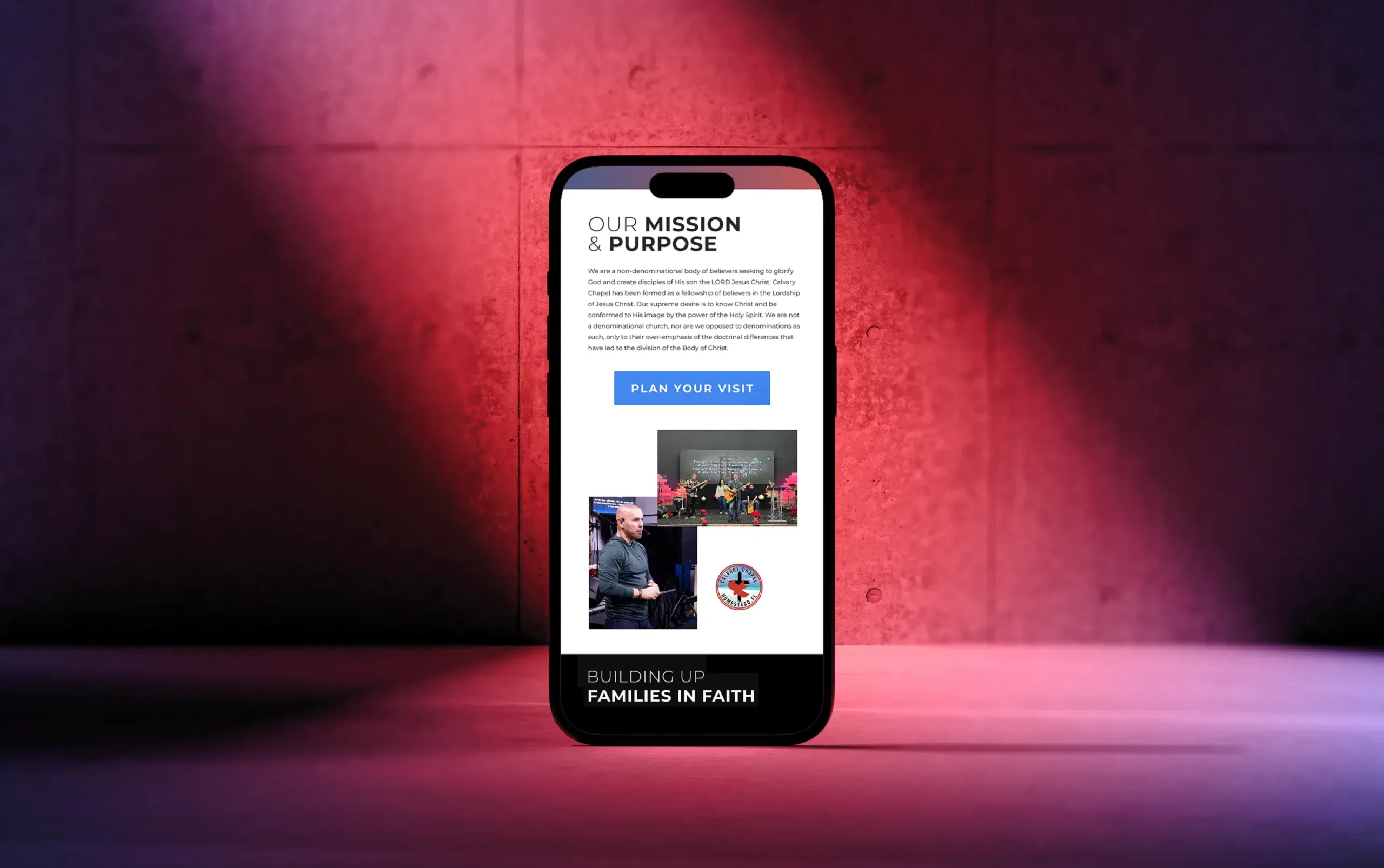 Smartphone displaying a mission and purpose webpage against a pink-lit brick wall background.