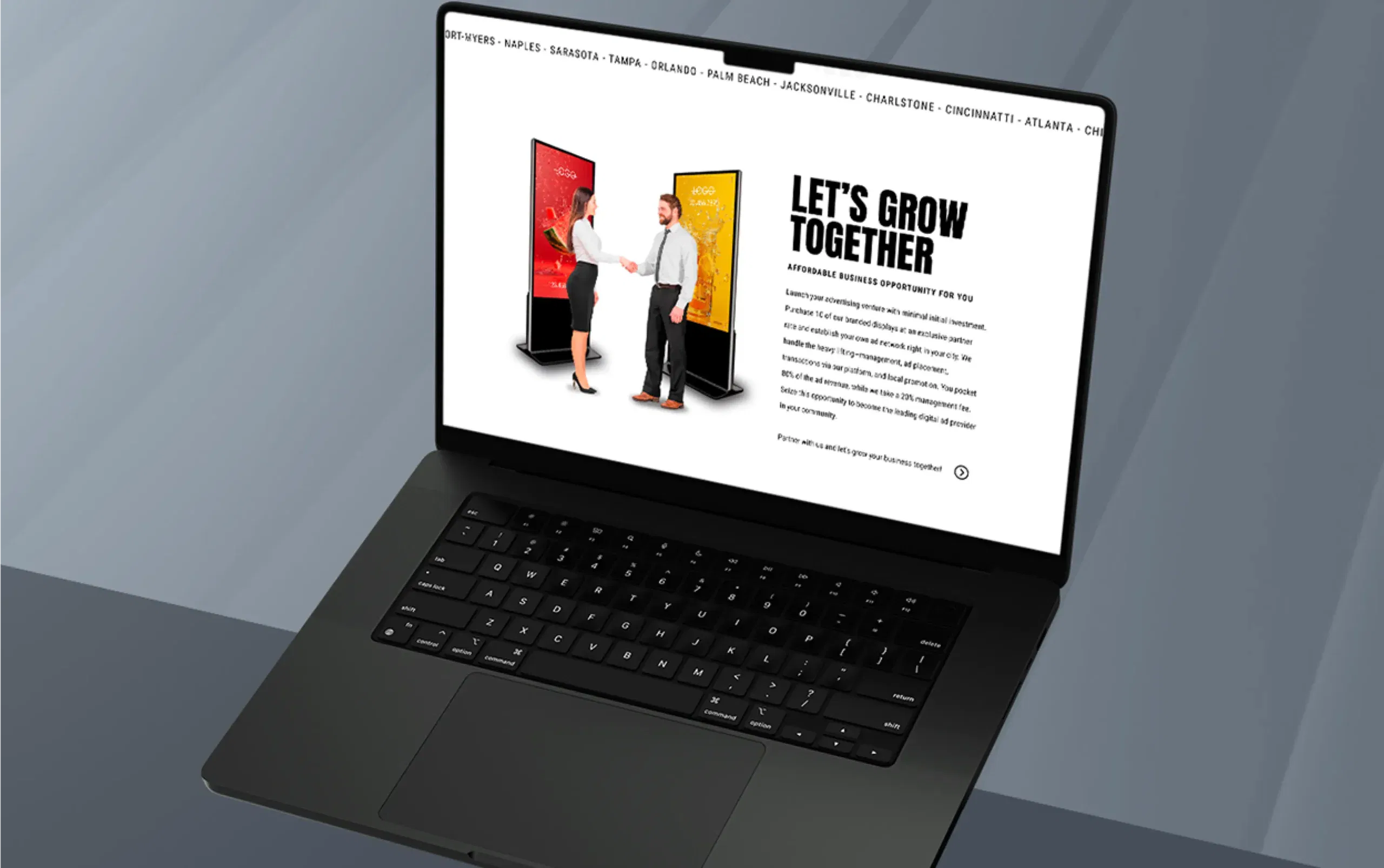 Open laptop displaying marketing content with two people in front of colorful digital displays.