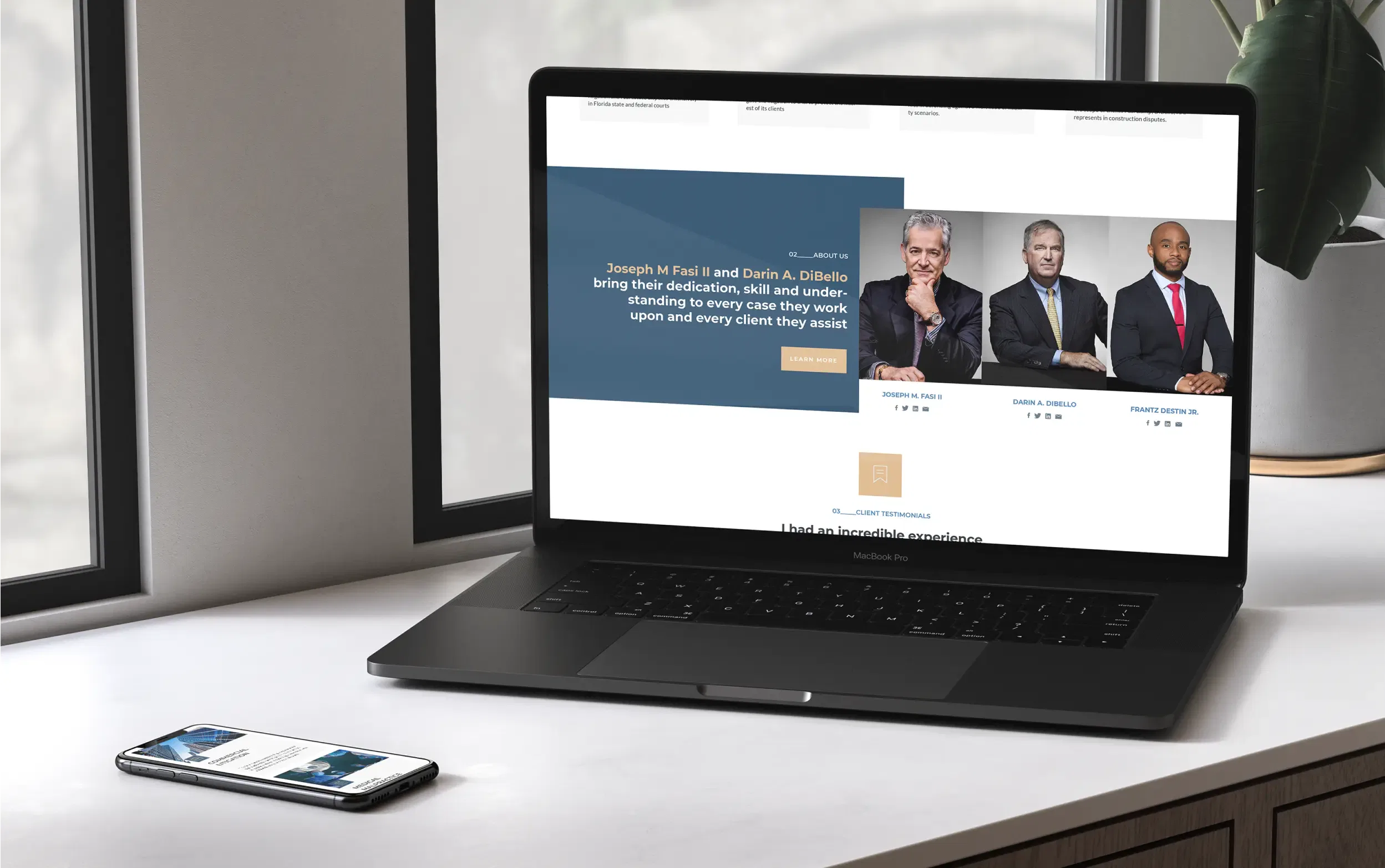 Laptop displaying a website with business professionals, accompanied by a smartphone on a windowsill.