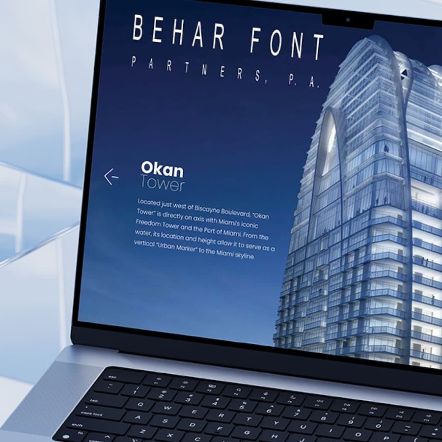 Laptop displaying an architectural design with a sleek, modern skyscraper and bold text.