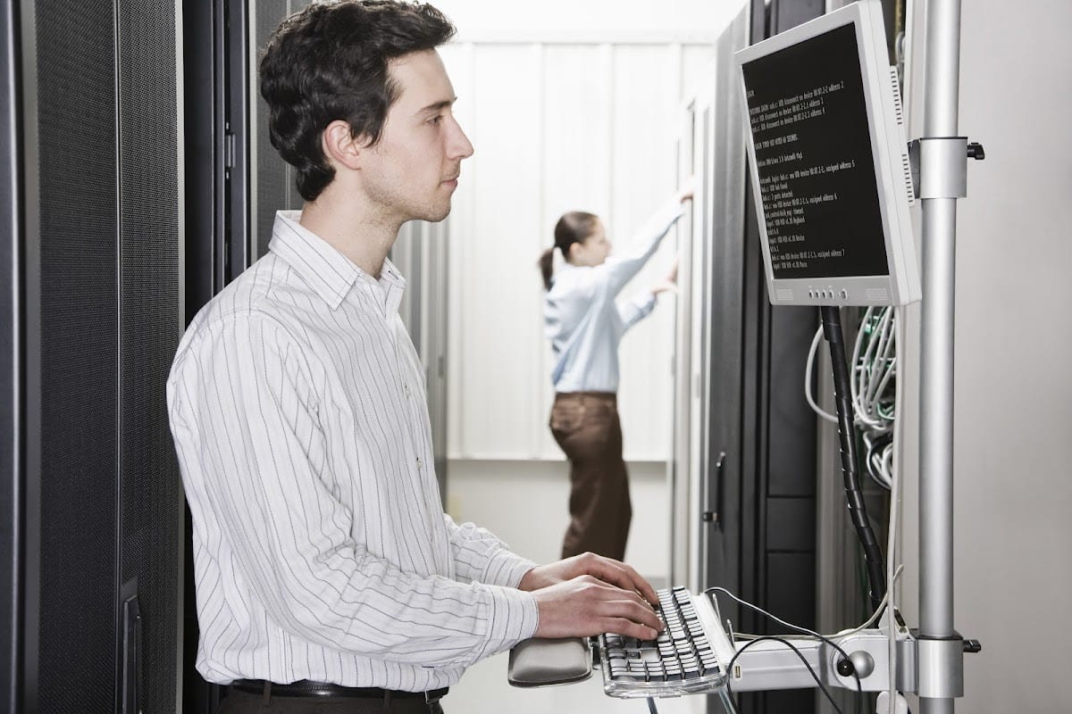 Male technician in server room working on computer terminal.