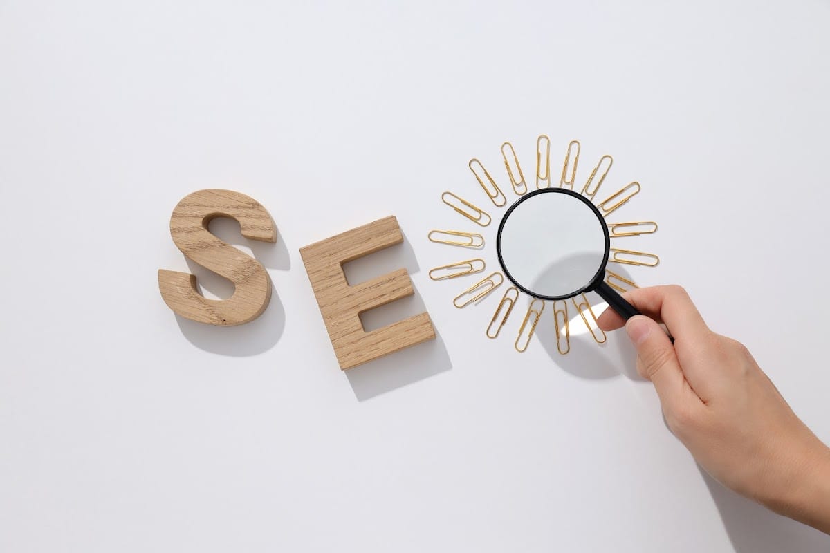 SEO concept with wooden letters and magnifying glass on white background.