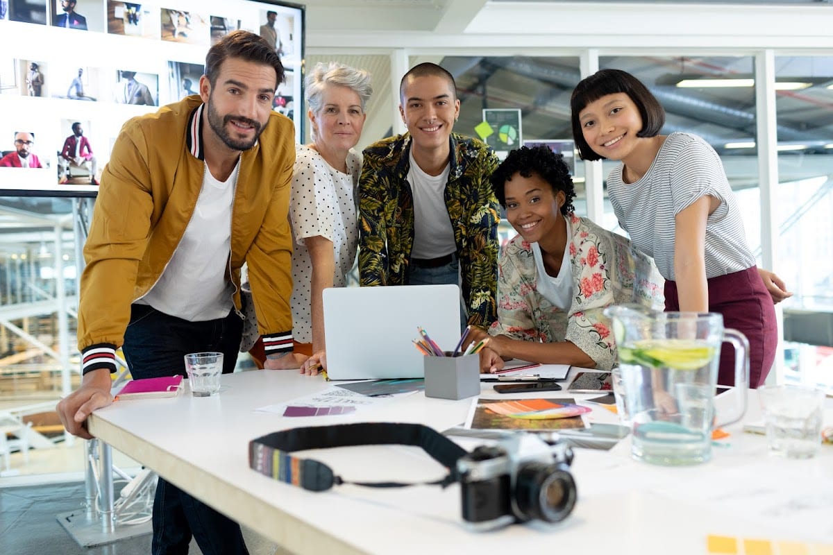 Diverse business team collaborating around a laptop at a modern office table.