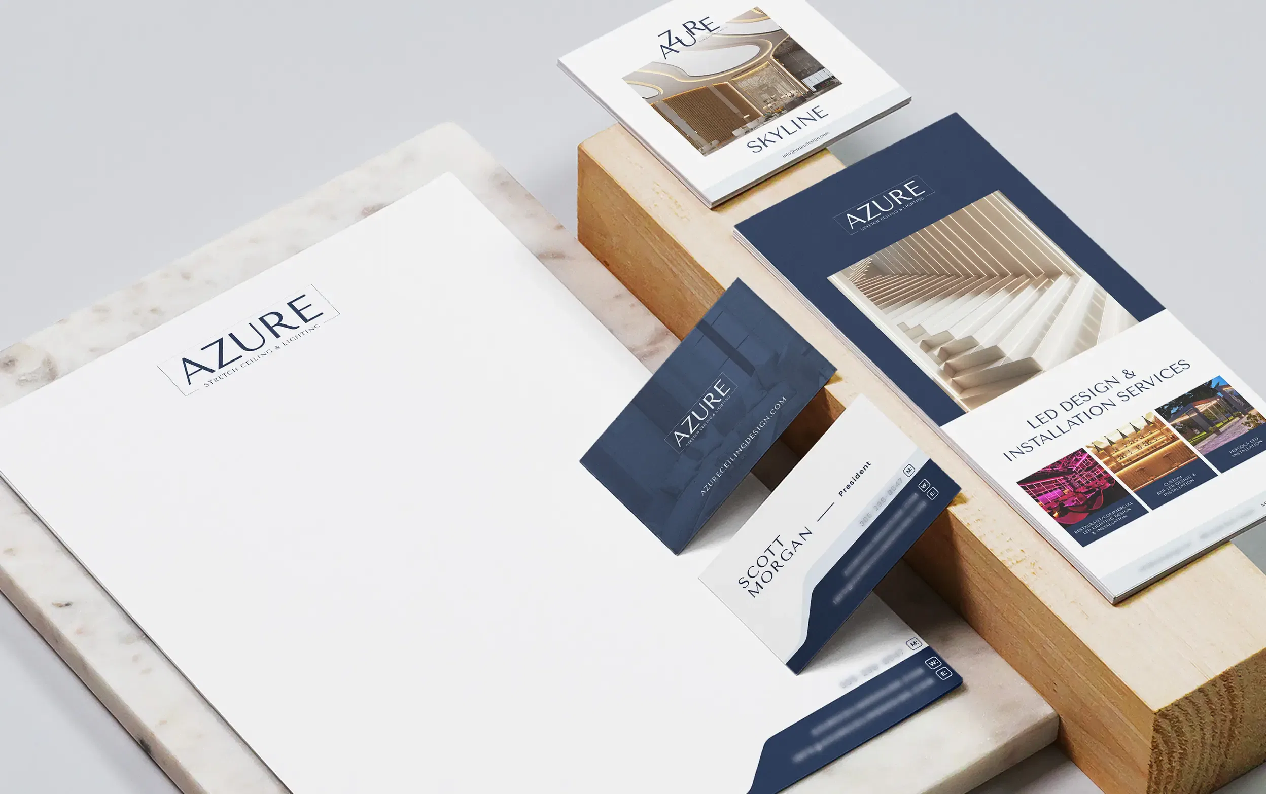Elegant Azure stationery set with business cards, brochures, and letterhead on wooden and marble surfaces.