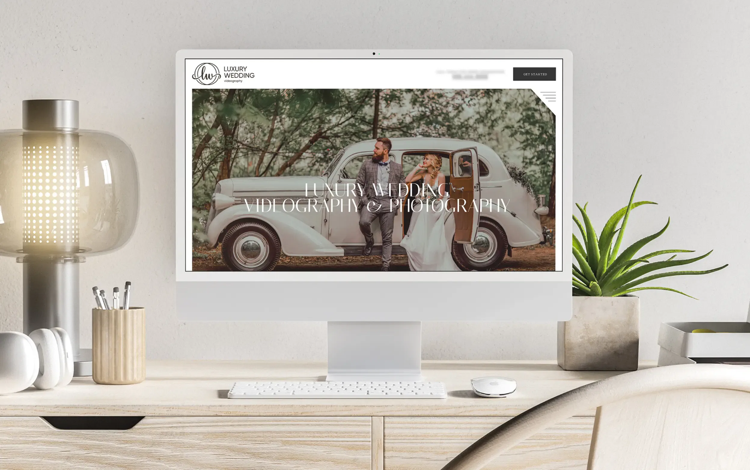 Computer screen displaying a classic wedding car photo, set on a modern desk with plants and office supplies.