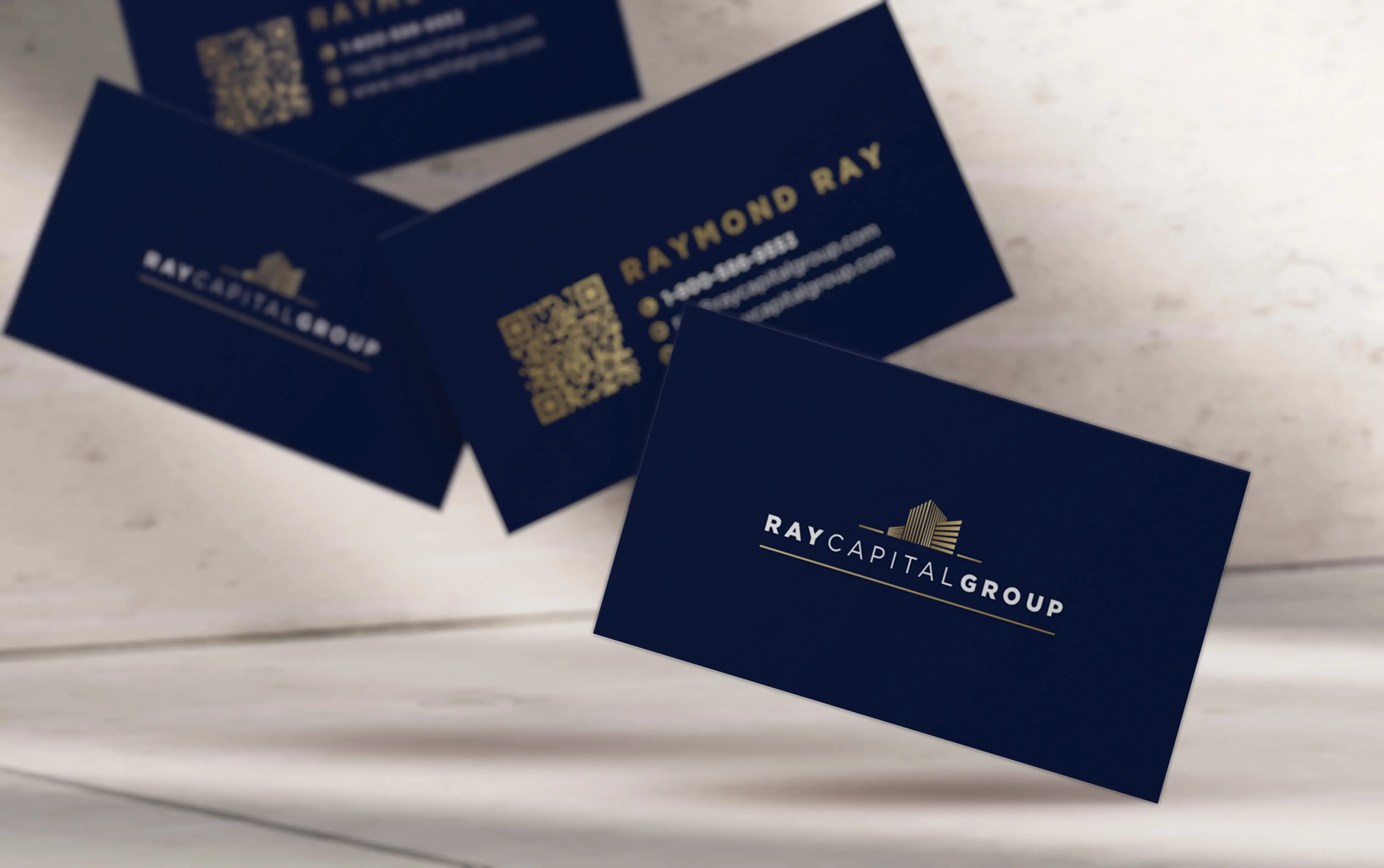 Floating black business cards with gold details for Raymond Capital Group.