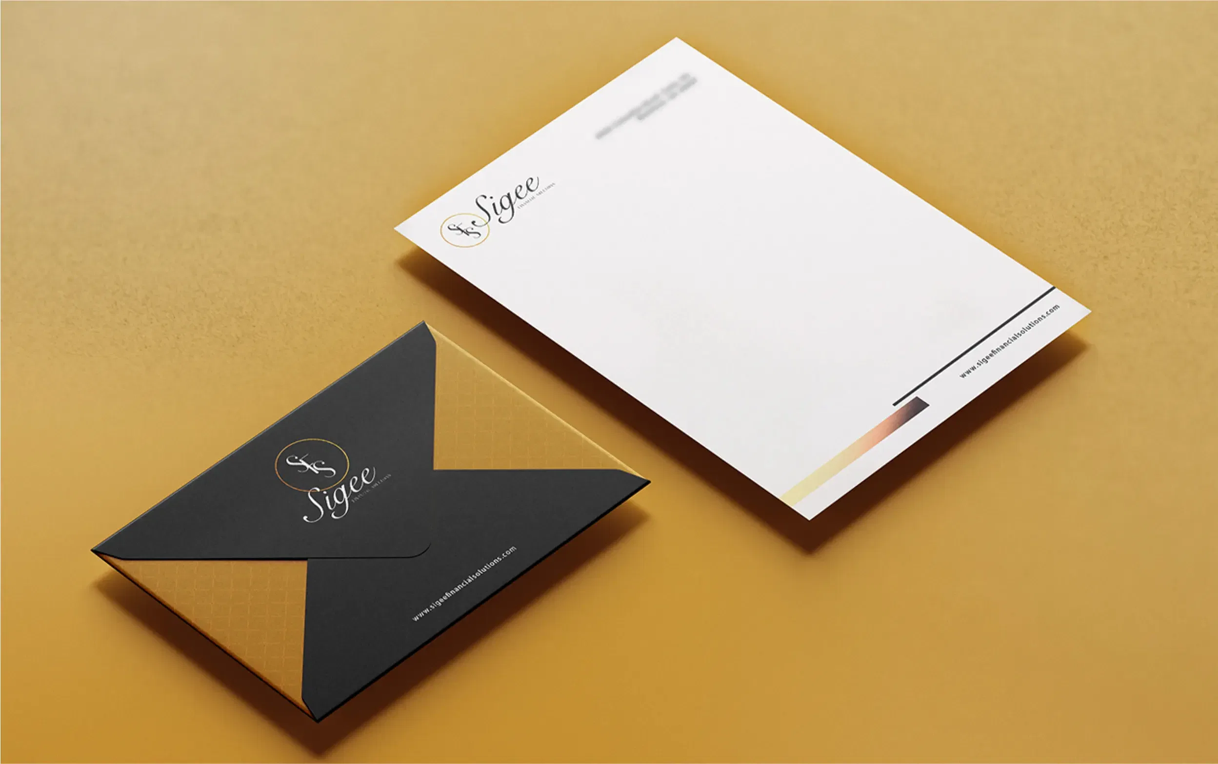 Elegant black and gold envelope beside a matching letterhead on a warm yellow surface.