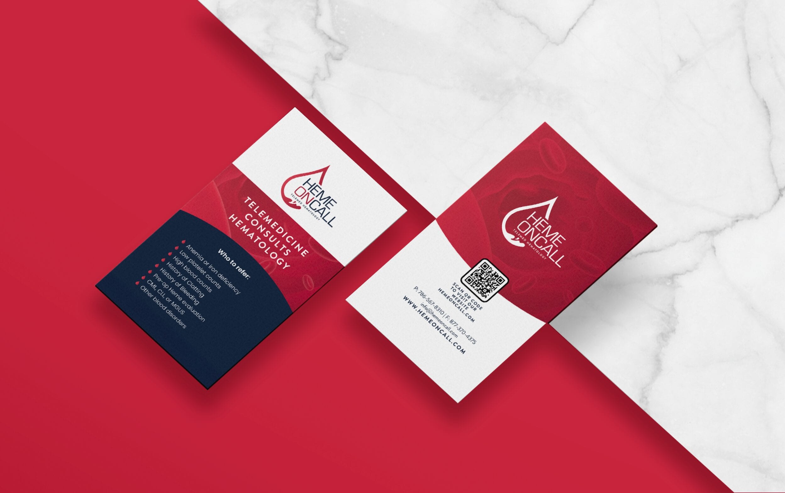 Professional business cards with a red and white design on a marble background.