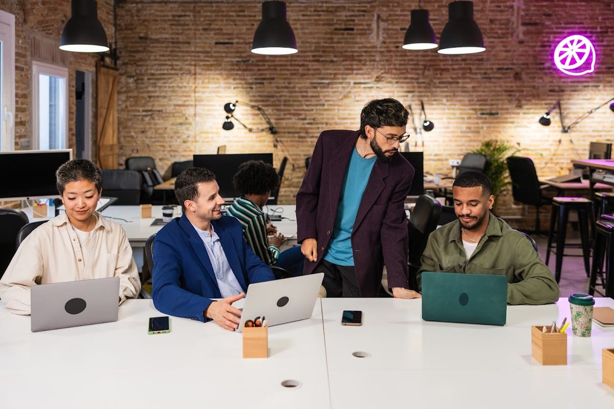 Diverse team collaborating on laptops in a modern office setting.