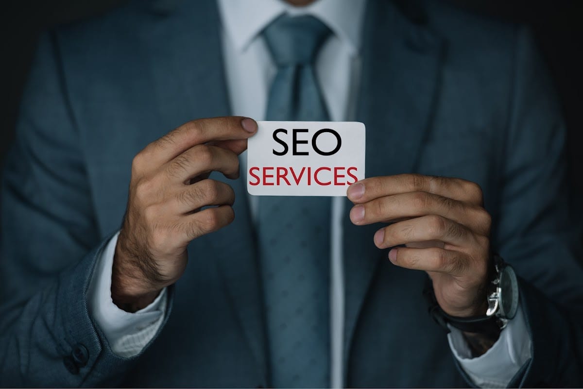 Business professional in suit holding a card displaying SEO services.