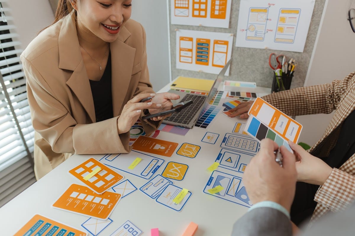 Designers collaborate on creative website layouts with colorful prototypes and digital tools.